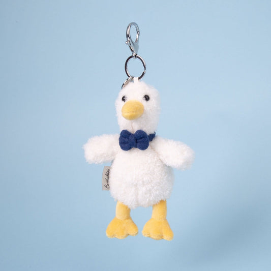 Plush duck keychain with a blue bow tie on a light blue background