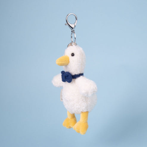 Plush duck keychain with a blue bow tie on a light blue background
