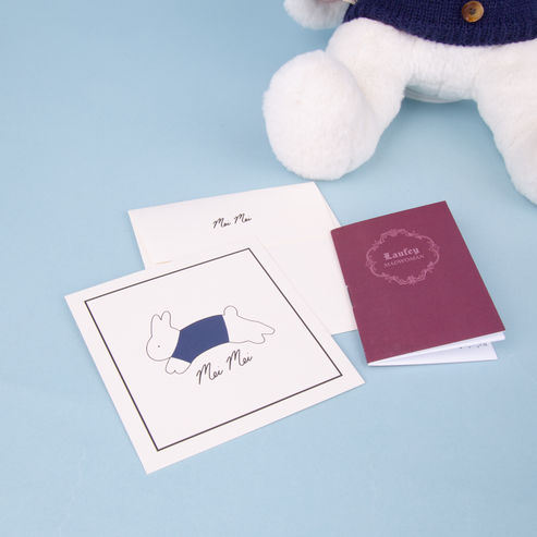 Set of stationery items including a card, notebook, and plush toy on a light blue background