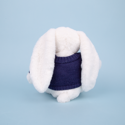 White plush toy rabbit wearing a navy blue sweater on a light blue background