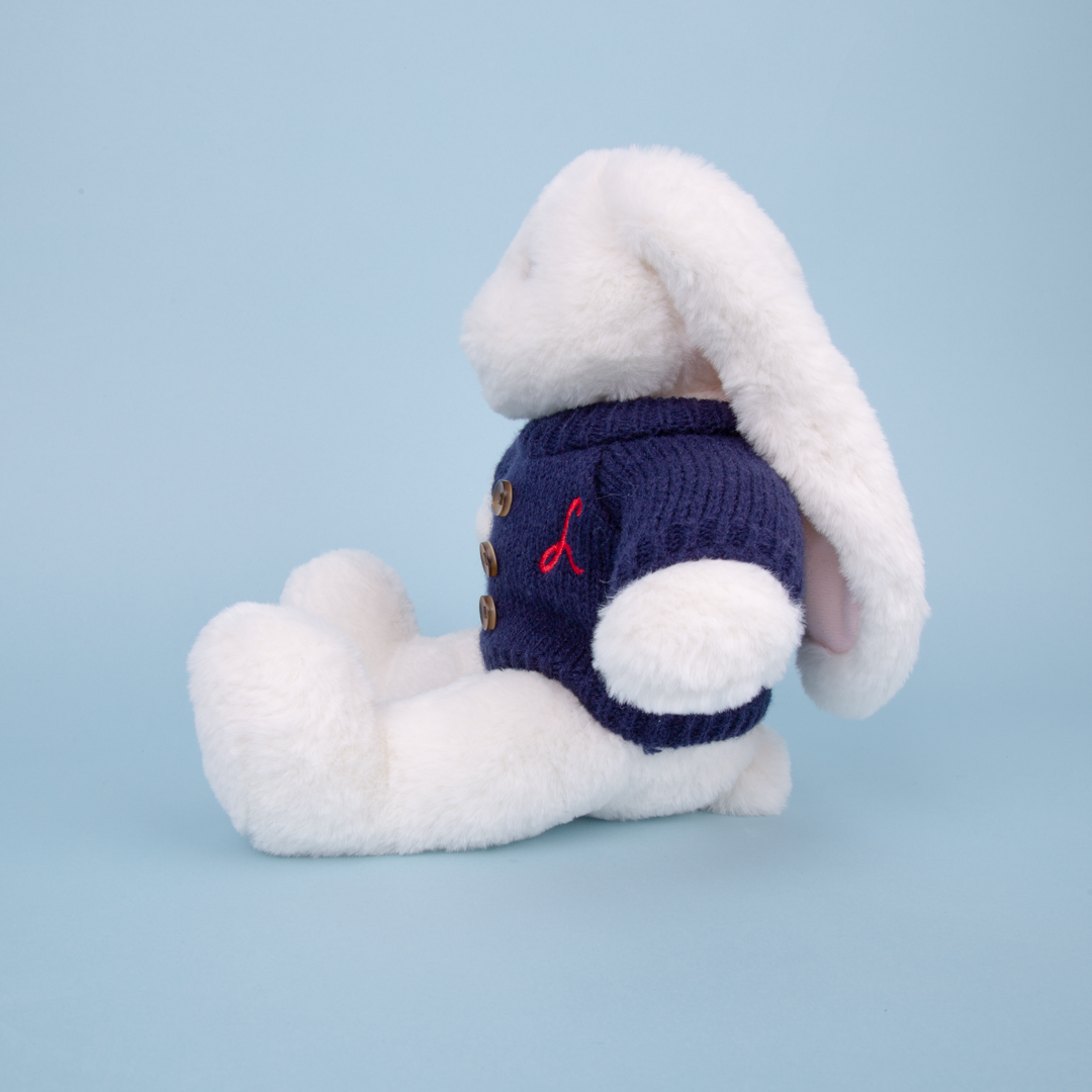 White plush bunny toy wearing a blue sweater with a red L embroidered on a light blue background