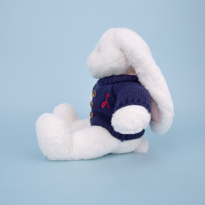 White plush bunny toy wearing a blue sweater with a red L embroidered on a light blue background